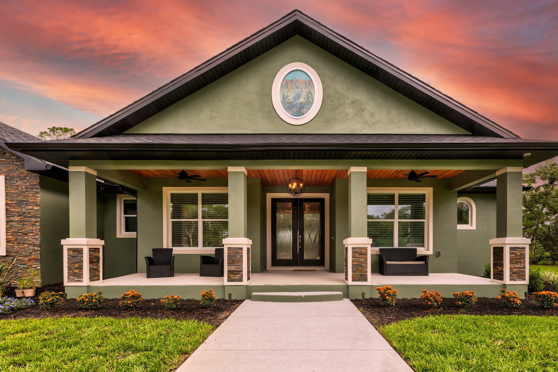 front porch exterior of house painted antique green with river stone decorative trim on pillars and adjacent facade